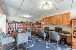 A cozy library with bookshelves, computers, and seating areas.