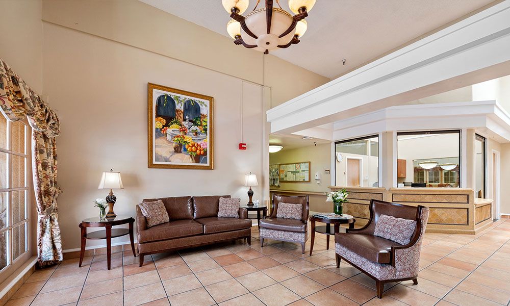 A hotel lobby featuring a comfortable seating area with sofas and chairs, elegant decor including a chandelier and artwork on the wall.