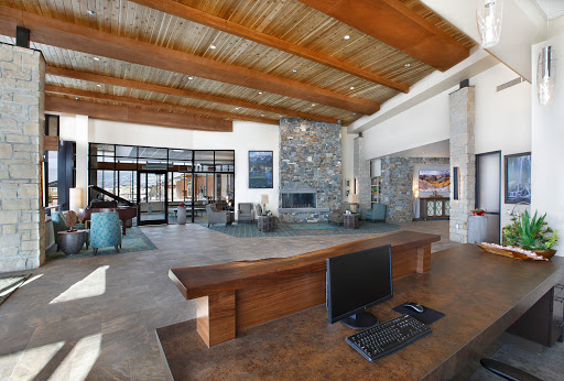A spacious and modern lobby featuring wooden beams, a stone wall with a fireplace, and an inviting workspace.