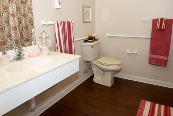 A modern bathroom with a toilet and sink featuring red and white towels for decor.