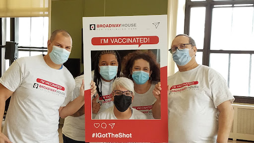 A group celebrating their vaccination with smiles and masked faces.