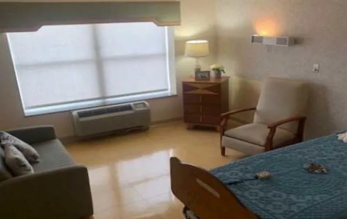 A clean and well-lit hospital room with a bed and seating area.