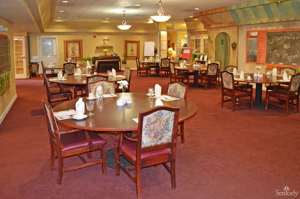 Spacious dining area with elegantly arranged tables and chairs, featuring warm lighting and decor.