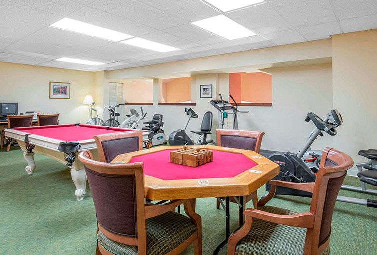 A multi-purpose room featuring a pool table, poker table, and exercise equipment.