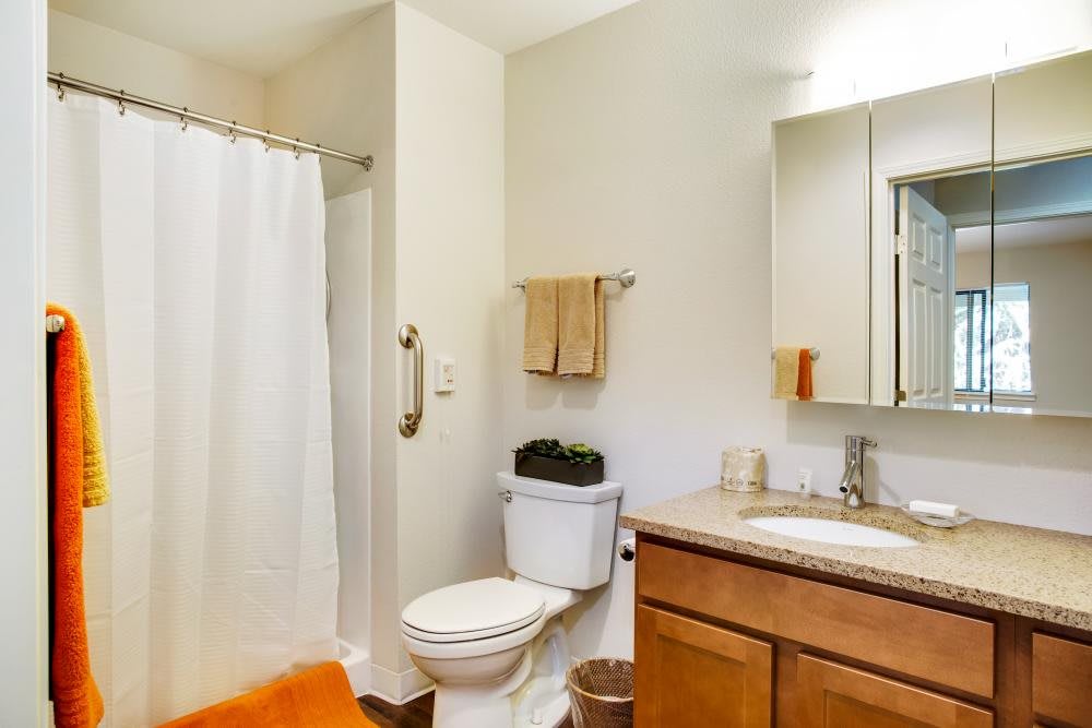 A well-organized bathroom featuring a toilet, sink with a wooden cabinet, and a shower area with a white curtain.