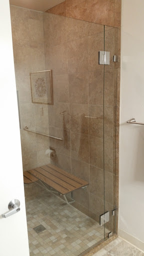 A modern glass shower space featuring a wooden bench and elegant tilework.