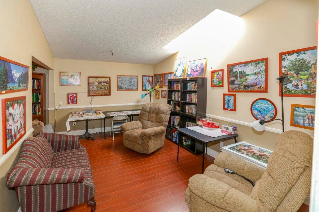A cozy living room with comfortable seating, bookshelves, and various paintings on the walls.