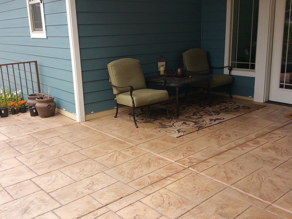 A cozy outdoor patio area with chairs, a table, and a decorative rug.