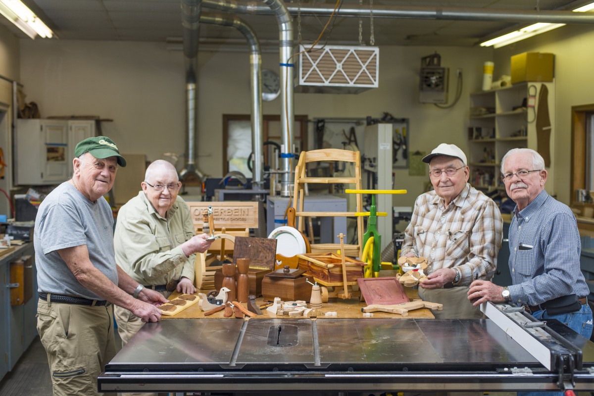 A group of craftsmen showcasing their woodworking projects in a workshop.