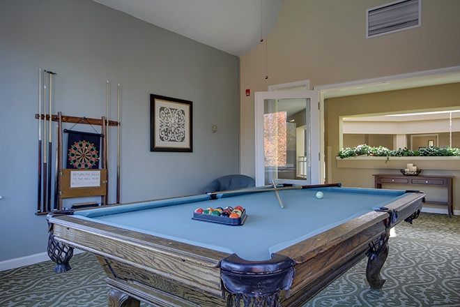 A cozy game room featuring a well-maintained pool table with cues and balls ready for play.