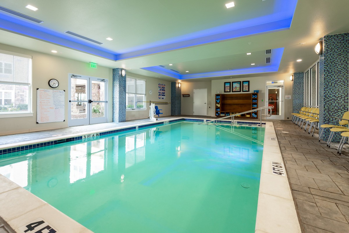 A bright indoor swimming pool with modern lighting in a hotel setting.
