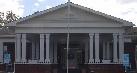 A symmetrical building entrance with columns and a porch.