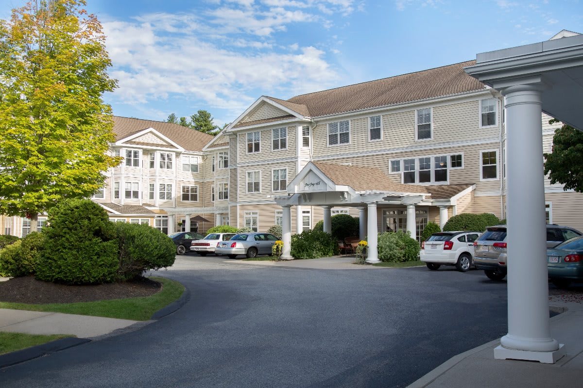 A large residential building with parked cars in front and a clear blue sky.