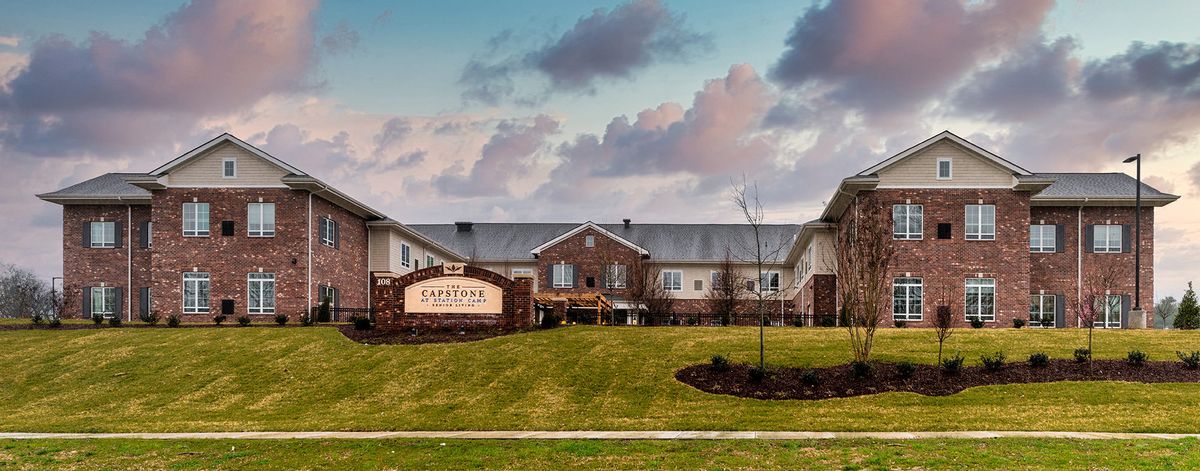 A modern building with a landscaped lawn under a cloudy sky.