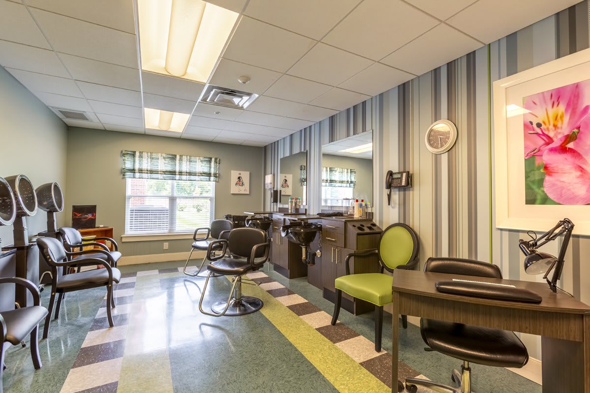 A well-organized hair salon with chairs, mirrors, and striped wallpaper.