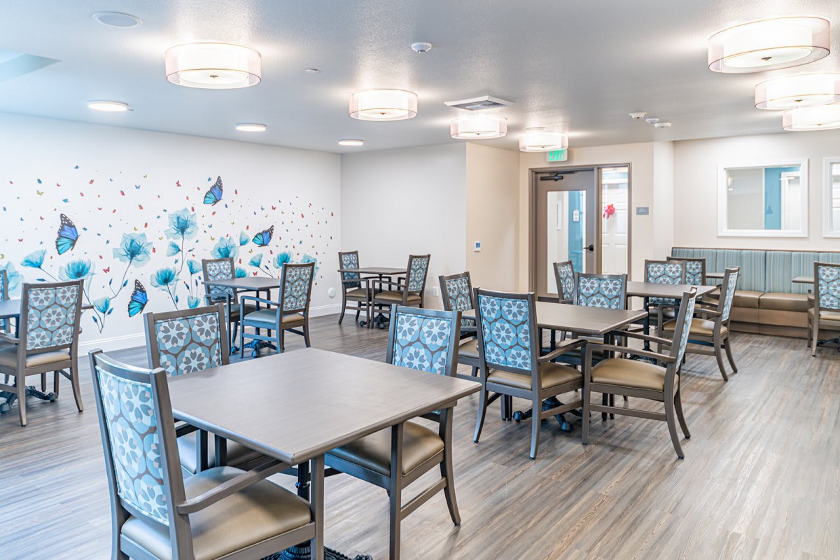 A modern dining room with neatly arranged tables and chairs, featuring decorative wall art.
