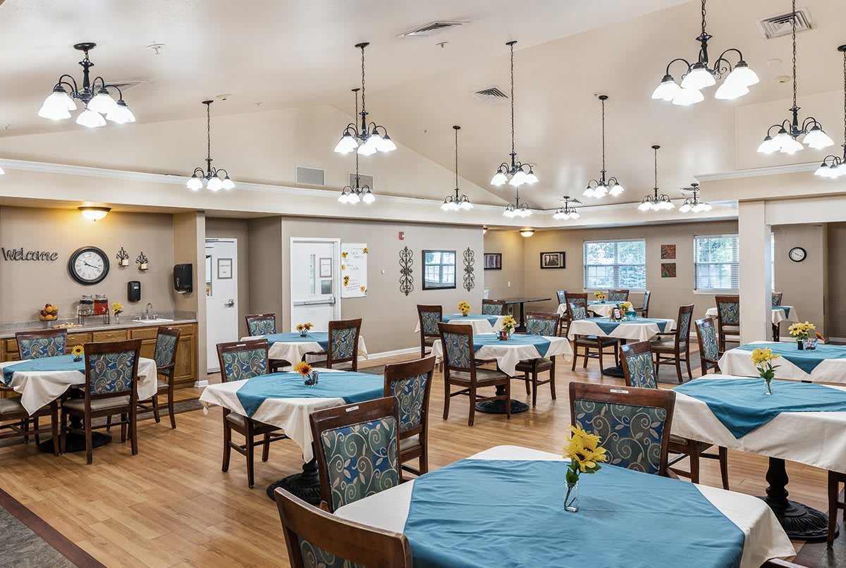 A spacious dining room with neatly arranged tables and chairs, featuring elegant decor and warm lighting.