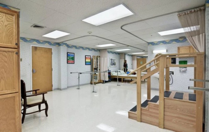 A spacious rehabilitation center room equipped with exercise stairs and parallel bars for physical therapy.