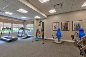 A spacious and well-lit gym with various fitness equipment, including a treadmill and exercise machines.