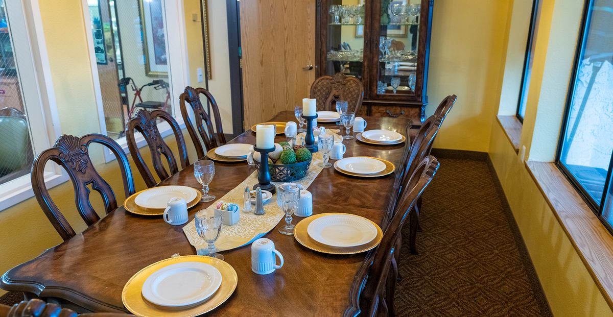 A well-set dining table with plates, cups, and candles in a cozy dining room.