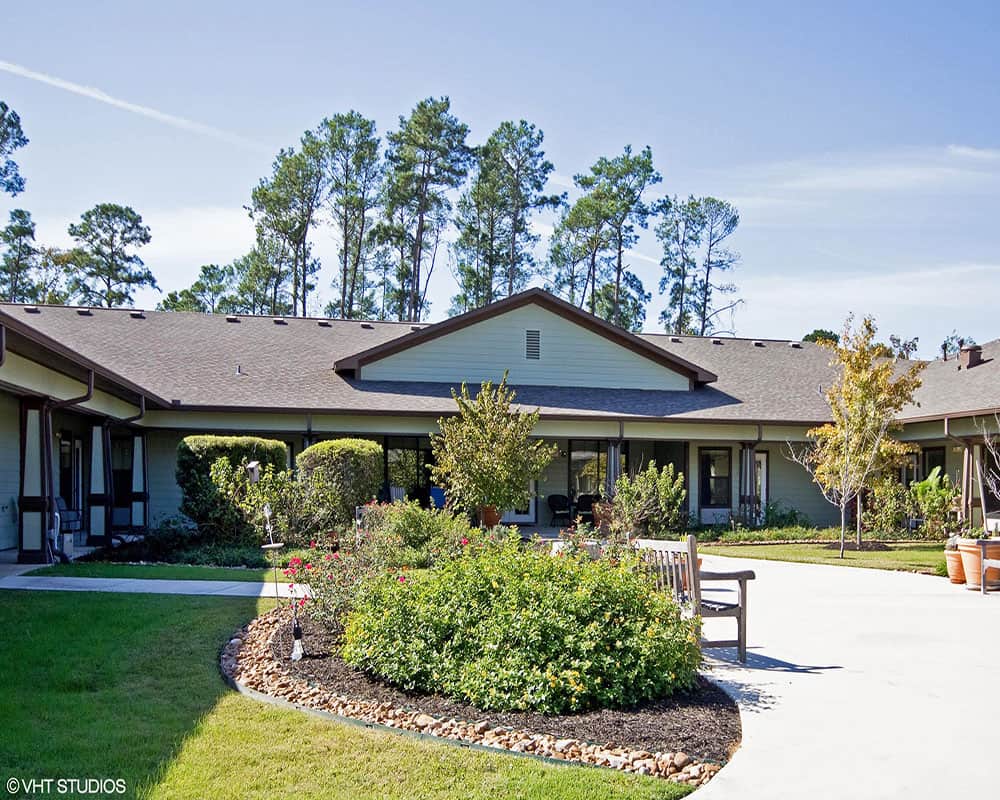 A scenic view of a single-story building surrounded by a landscaped garden and pathway.