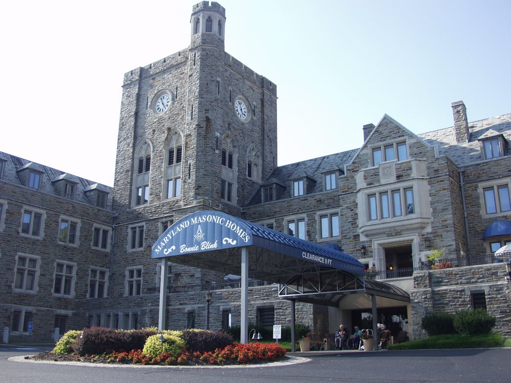 A stone building with a clock tower and a covered entrance.