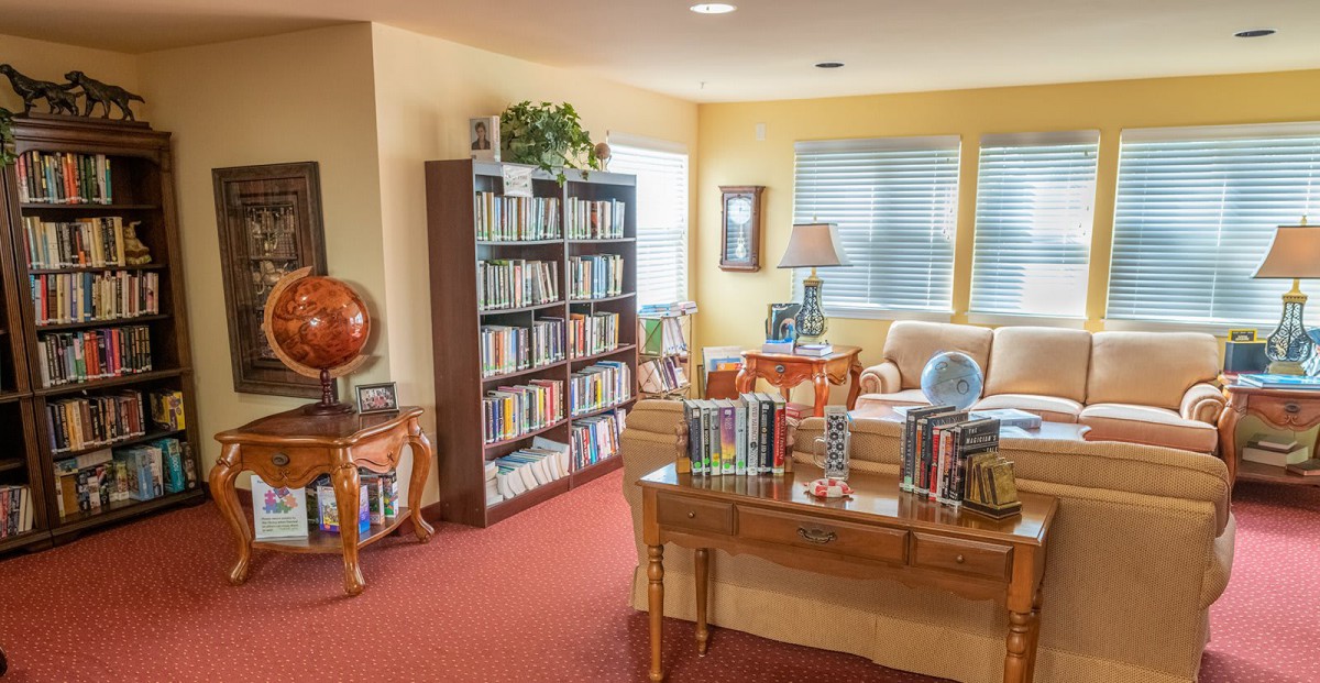 A cozy library room featuring bookshelves, a globe, and comfortable seating.