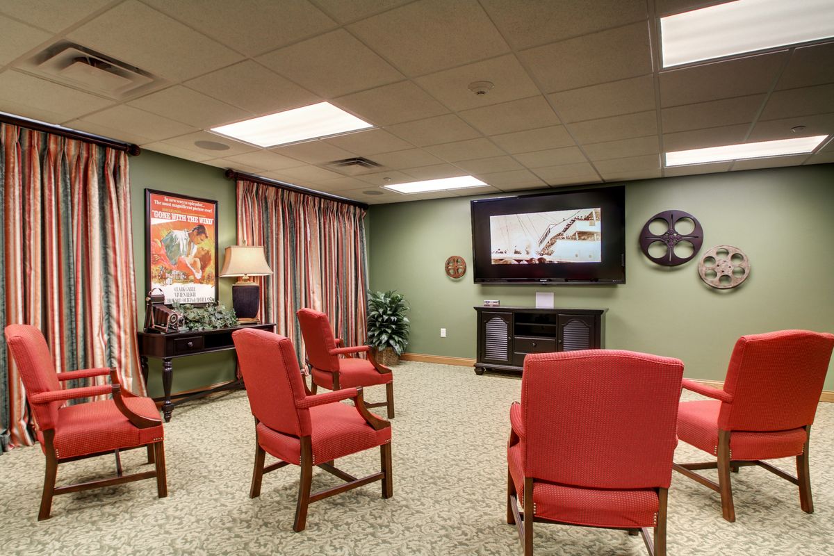 A cozy home theater setup with red chairs facing a large television in a warmly decorated room.
