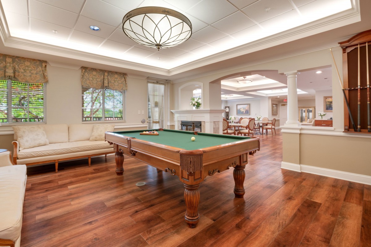 A luxurious game room featuring a billiard table with elegant wood flooring and ambient lighting.