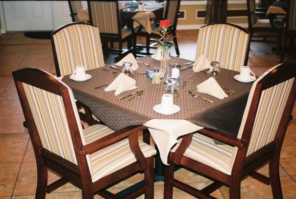 A neatly set dining table with striped chairs in a restaurant.