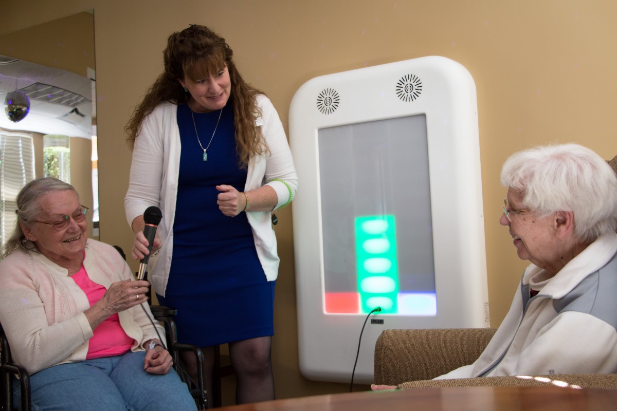 A group of seniors interacts with a healthcare monitoring device.