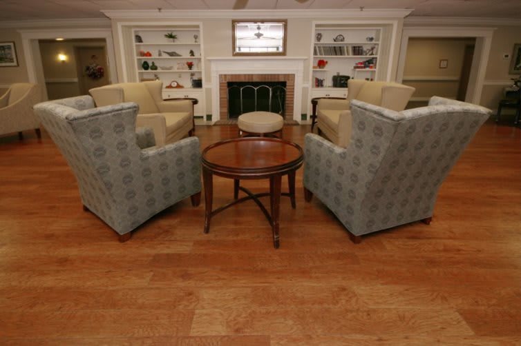 A cozy living room with four chairs around a coffee table, featuring a fireplace and built-in bookshelves.