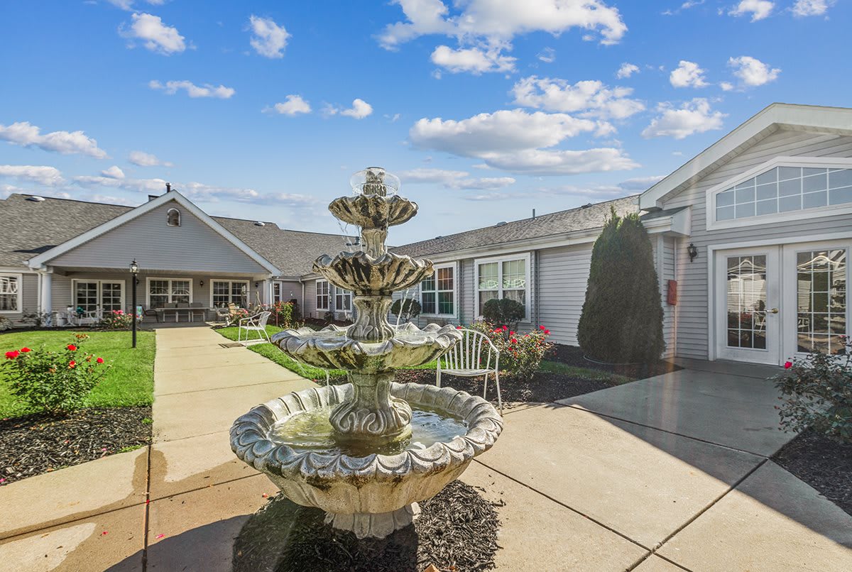 A serene courtyard featuring a decorative fountain under a bright blue sky.