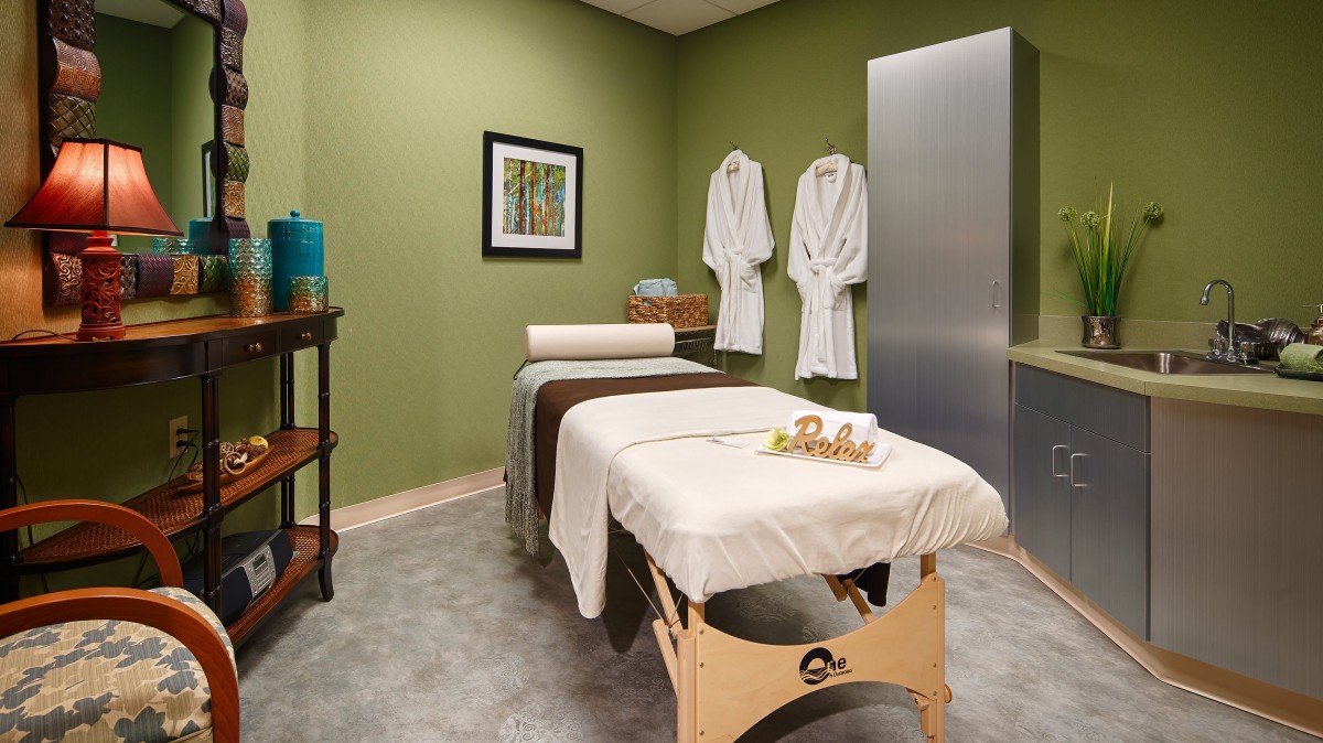 A tranquil spa room with a massage table and robes, set for a relaxing therapy session.