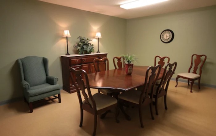 A neatly arranged dining room with a wooden table, chairs, and sideboard.