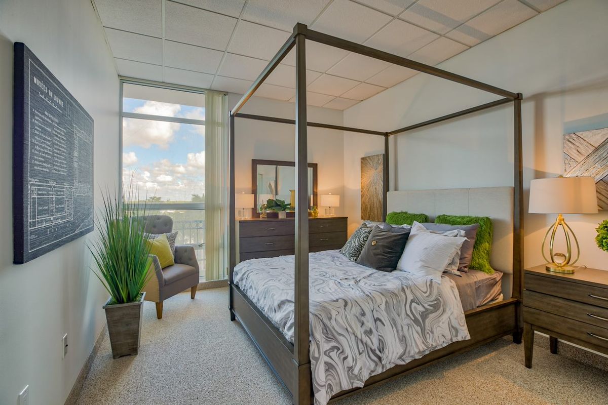A modern bedroom featuring a stylish canopy bed, natural lighting, and tasteful decor.