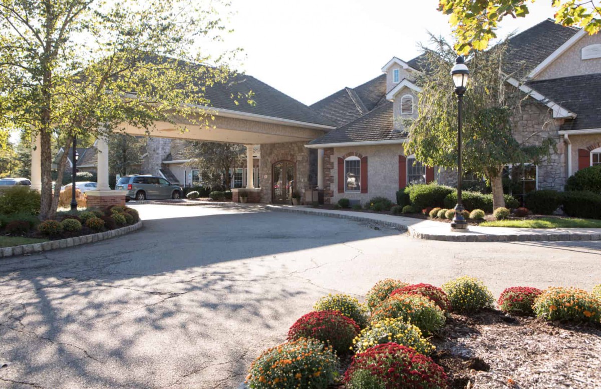 Entrance of a building with a driveway and landscaped surroundings.