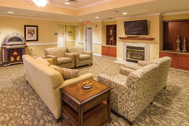 A cozy living room with comfortable seating arrangements, a fireplace, and a wall-mounted television.