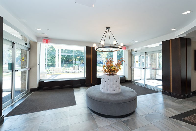 A modern lobby with stylish decor, featuring a central seating area and large windows.