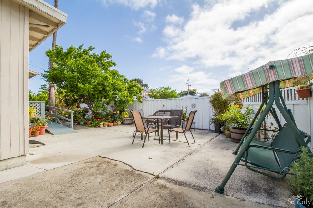 A sunny patio with outdoor furniture and lush greenery.