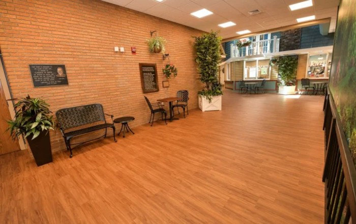 A spacious indoor lobby with seating, tables, and decorative plants.