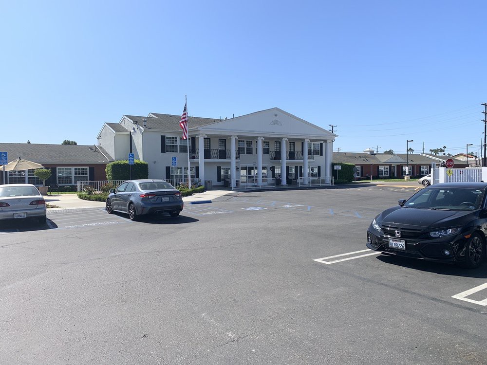 A sunny day view of a building with cars parked in front and an American flag waving.
