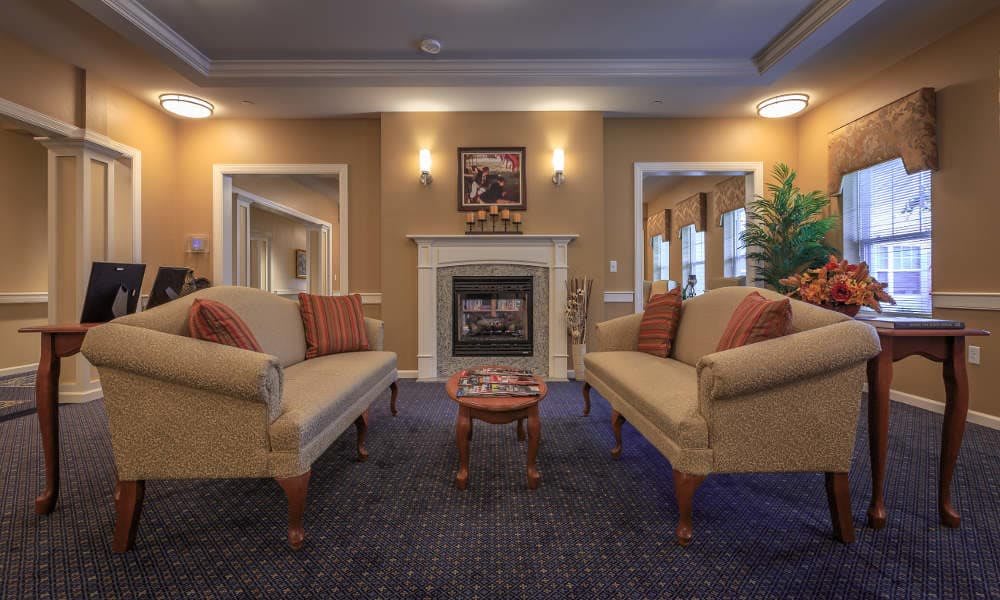 A cozy traditional-style living room with two sofas facing a fireplace.