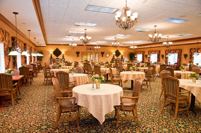 An elegant dining hall with neatly arranged tables and chandeliers overhead.