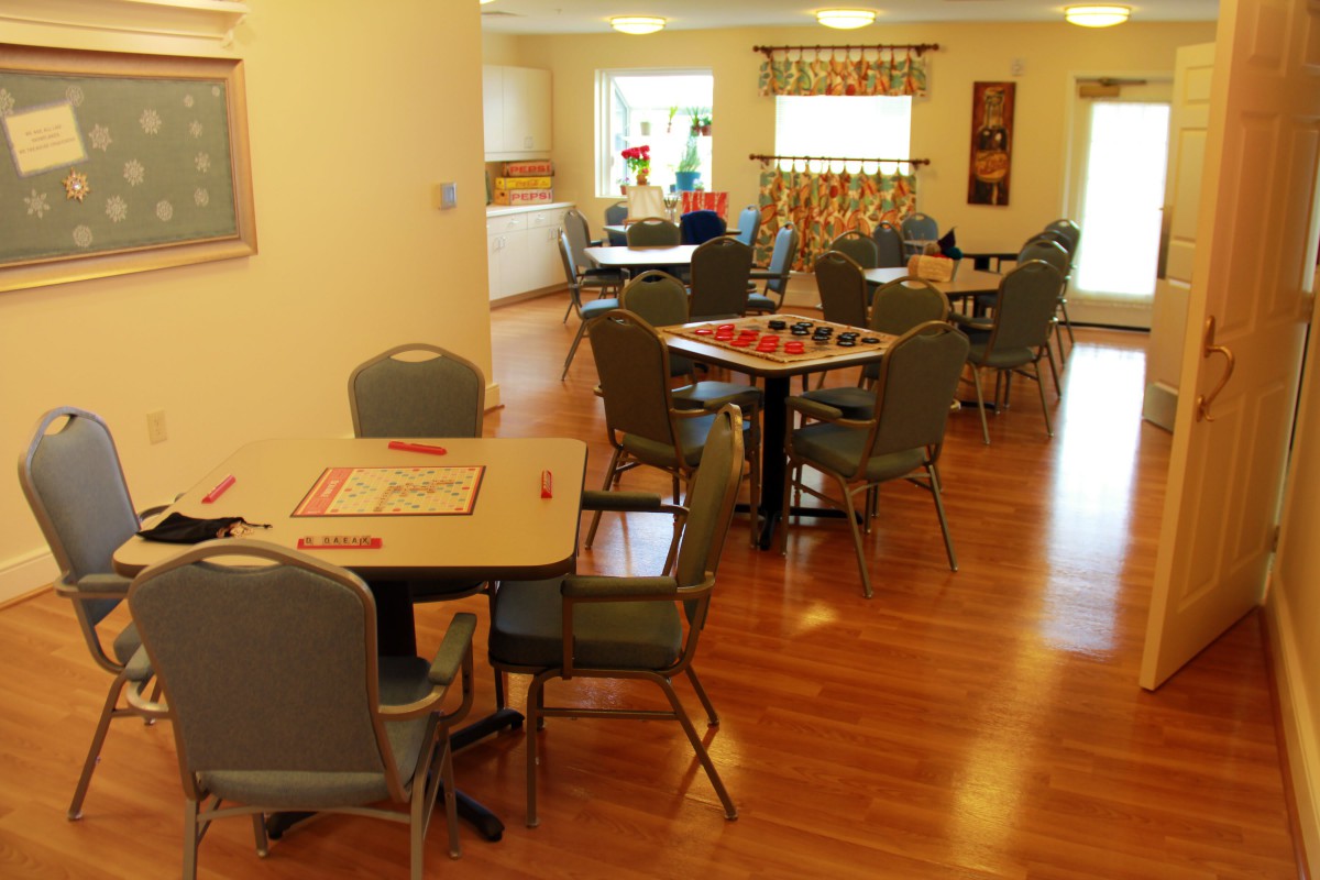 A bright and inviting community dining area with several tables and chairs arranged neatly on a wooden floor.