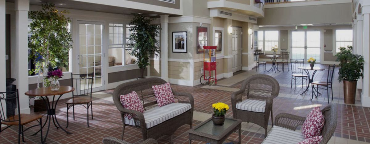 A cozy indoor seating area with wicker sofas, decorative cushions, a popcorn machine, and potted flowers.