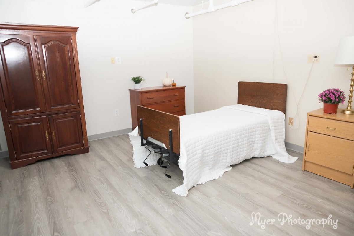 A minimalist bedroom with a wooden bed, dresser, and wardrobe.
