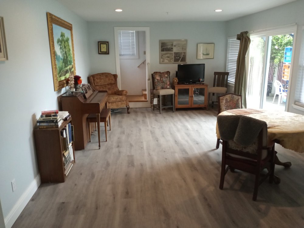 A cozy living room with a piano, television, and various pieces of furniture.