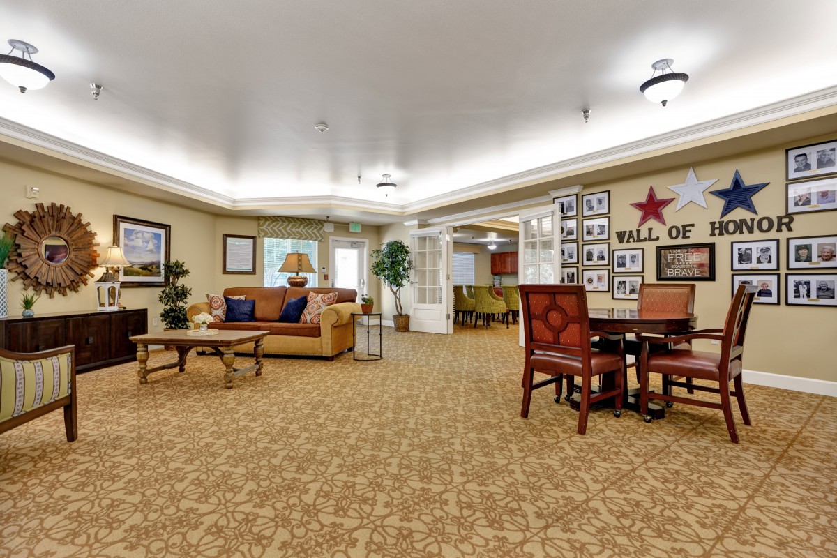 A spacious and well-decorated living room with comfortable seating, artwork on the walls, and ambient lighting.