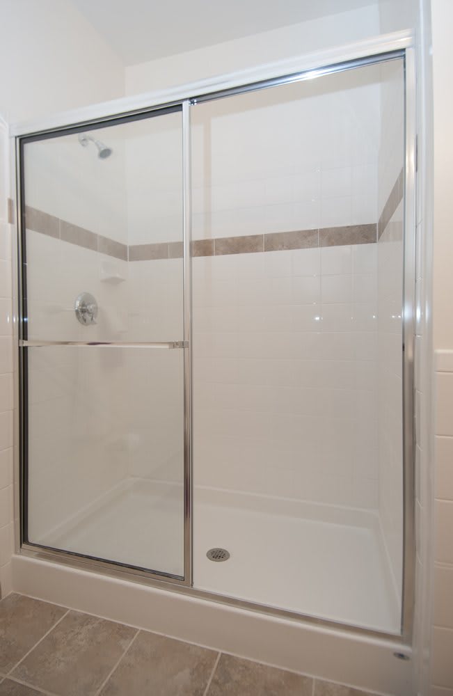 A modern shower enclosure with a glass sliding door and tiled walls.